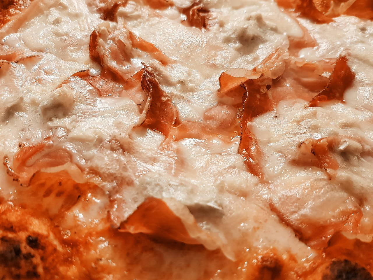 Pizza romana al taglio tagliata a rettangoli su banco di vendita, pasta dorata e croccante, olio lucido in superficie, sfondo di forno a legna acceso