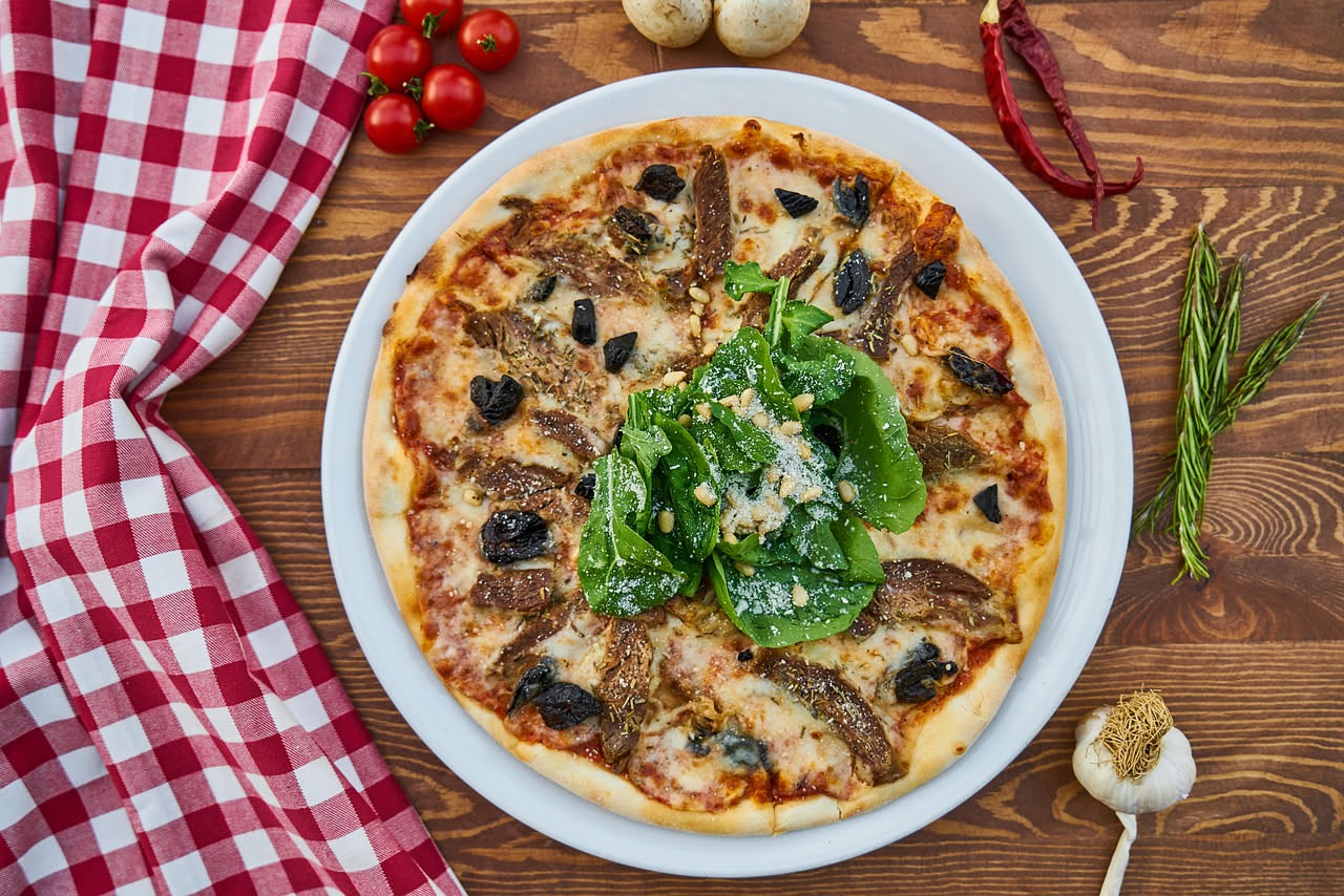 Pizza marinara appena sfornata con base croccante, sugo di pomodoro, aglio affettato e origano secco su un tavolo di legno antico