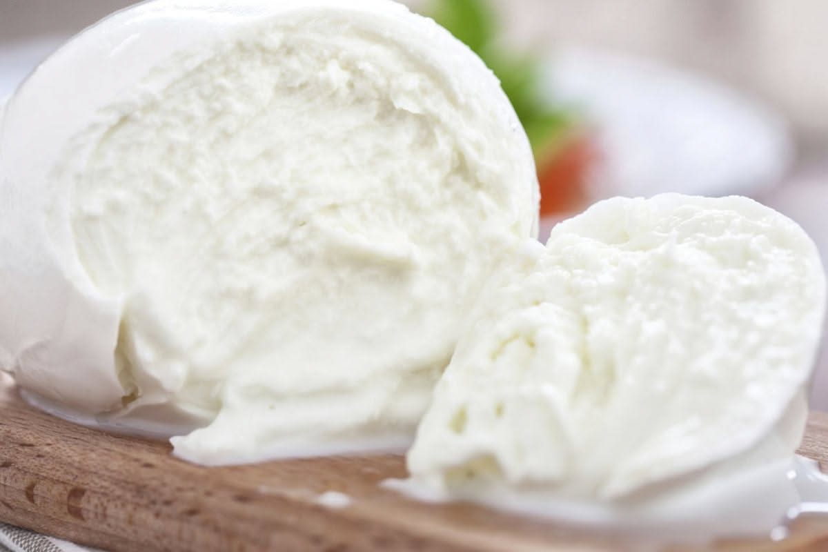 Mozzarella bianca fresca su carta assorbente bianca, con gocce d'acqua visibili e tessuto arrotolato accanto