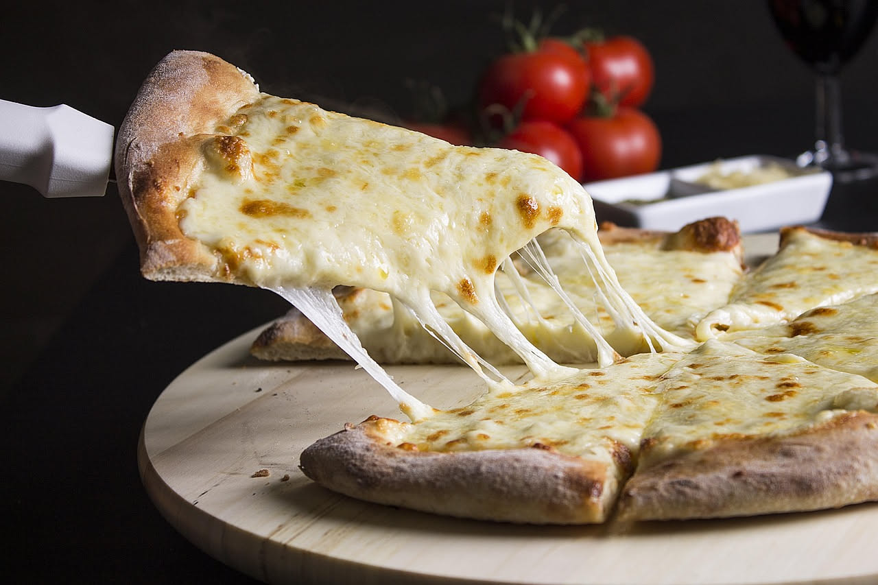 Formaggio fiordilatte bianco e lucido appena filato, ancora caldo, su un tavolo di acciaio inox in un caseificio con attrezzatura moderna sullo sfondo