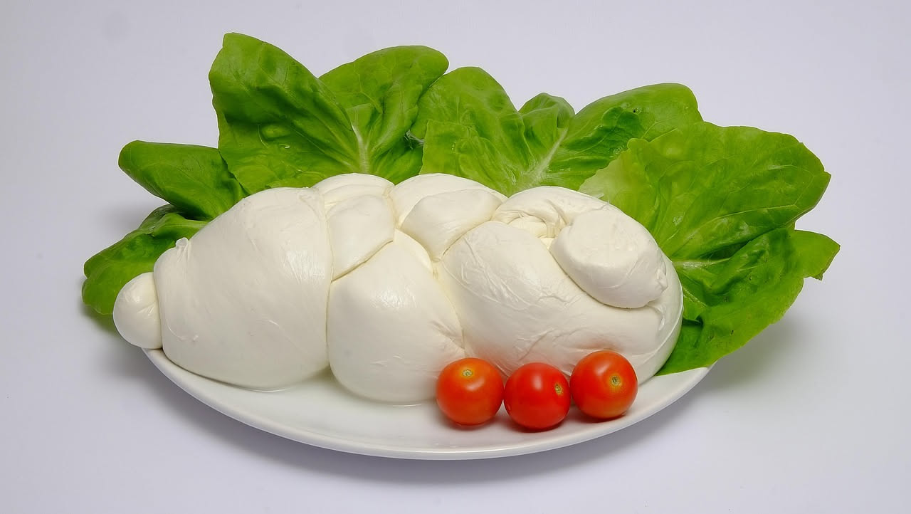Mozzarella di bufala tagliata a metà, sezione trasversale che mostra la fibra bianca compatta, lucida e uniforme, con gocce di siero trasparente intorno