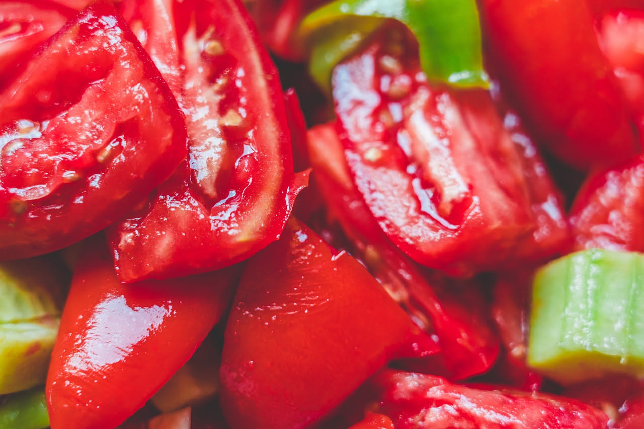Barattoli di pomodori San Marzano su uno scaffale di supermercato, alcuni con etichetta DOP e altri senza, accanto a una mano che legge l'etichetta
