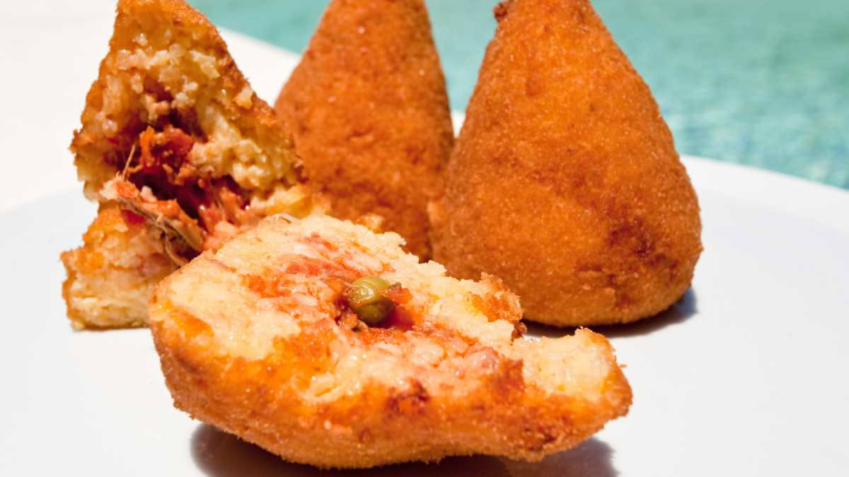 Pizza fritta napoletana tagliata in due, ripiena di ricotta bianca, cicoli dorati e mozzarella, servita su carta bianca oleata con vapore ancora visibile