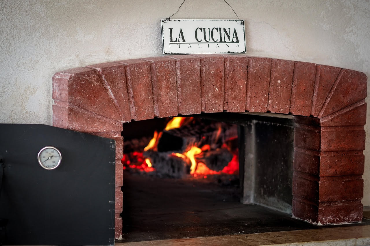 Primo piano di un sacco di farina bianca con etichetta che riporta percentuale di ceneri, accanto a chicchi di grano intero su superficie di legno