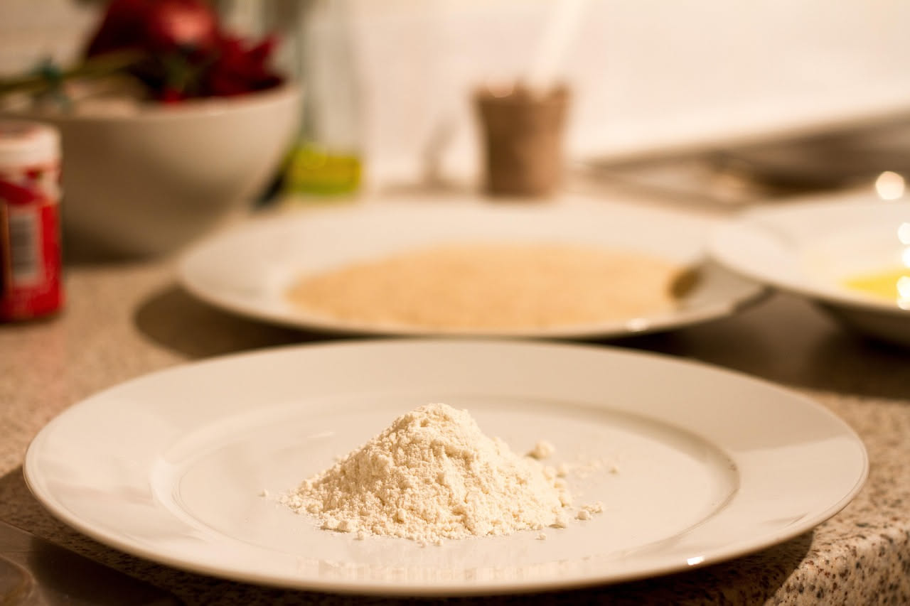 Pizzaiolo che versa olio extravergine di oliva su una pizza appena sfornata, ancora calda e fumante, nel forno a legna