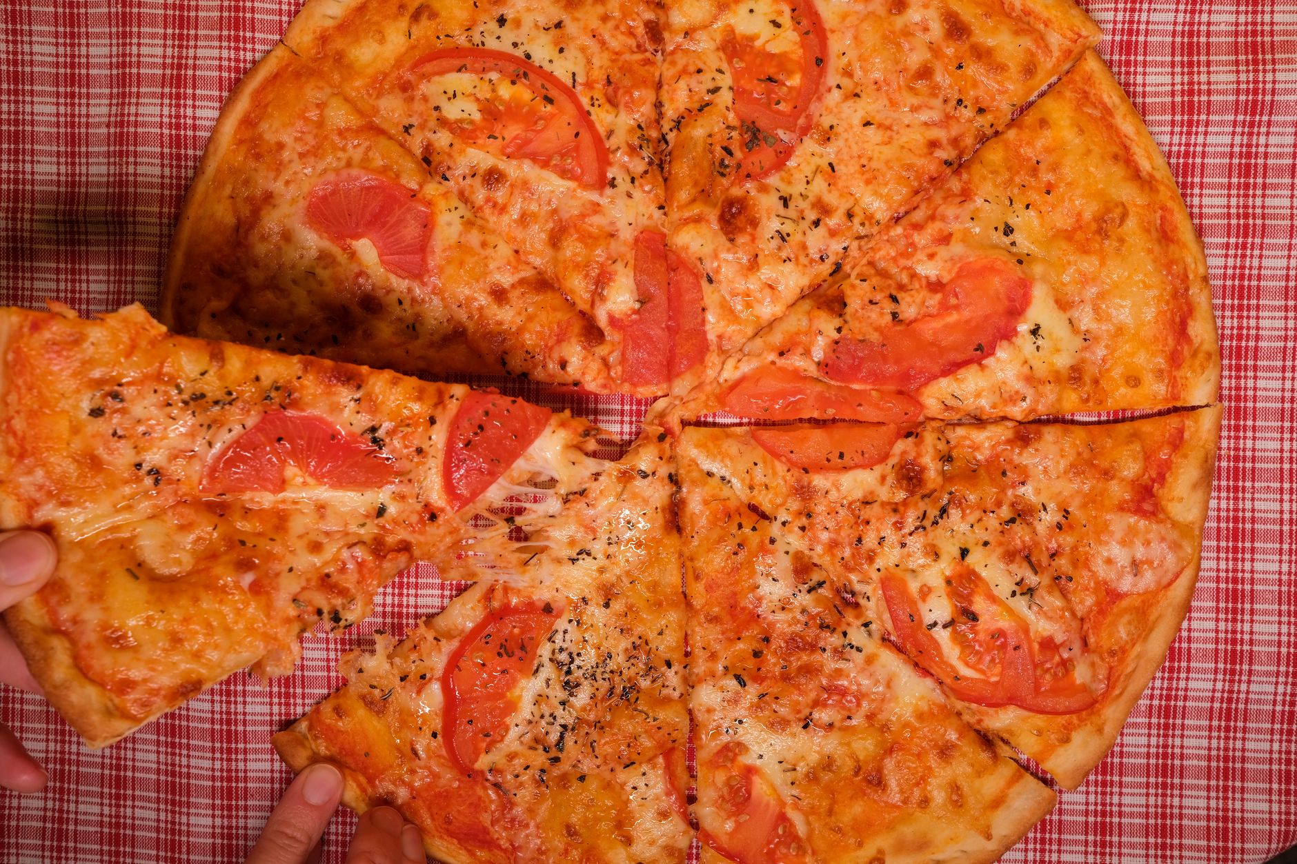 Teglia di pizza al taglio appena sfornata con cornicione dorato, margherita con mozzarella filante e basilico fresco su ripiano in acciaio di una pizzeria