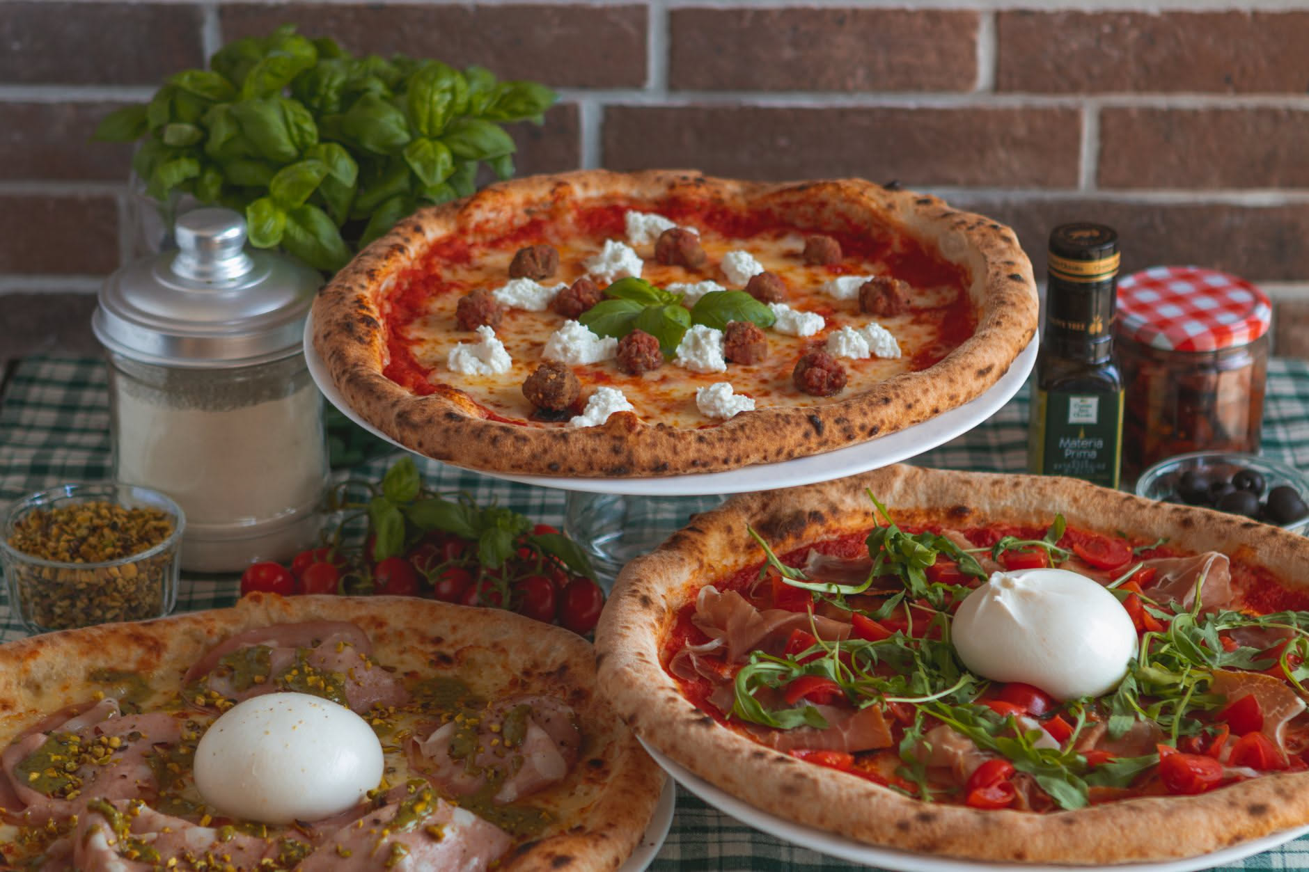 Interno di un forno a legna con pizza posizionata al centro della camera, base dorata e cornicione gonfio, fiamma sullo sfondo