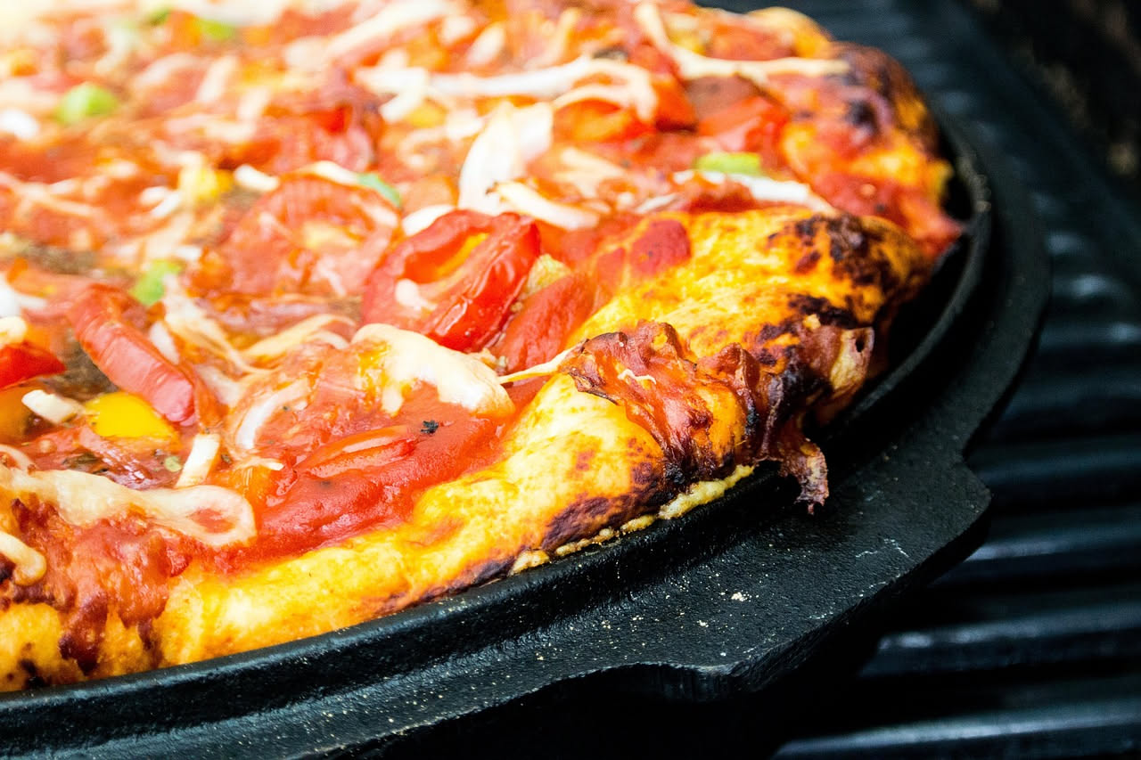 Fetta di deep dish di Chicago appena tagliata con formaggio filante che si distacca dal fondo della teglia, salsa di pomodoro rossa e crosta dorata ai bordi