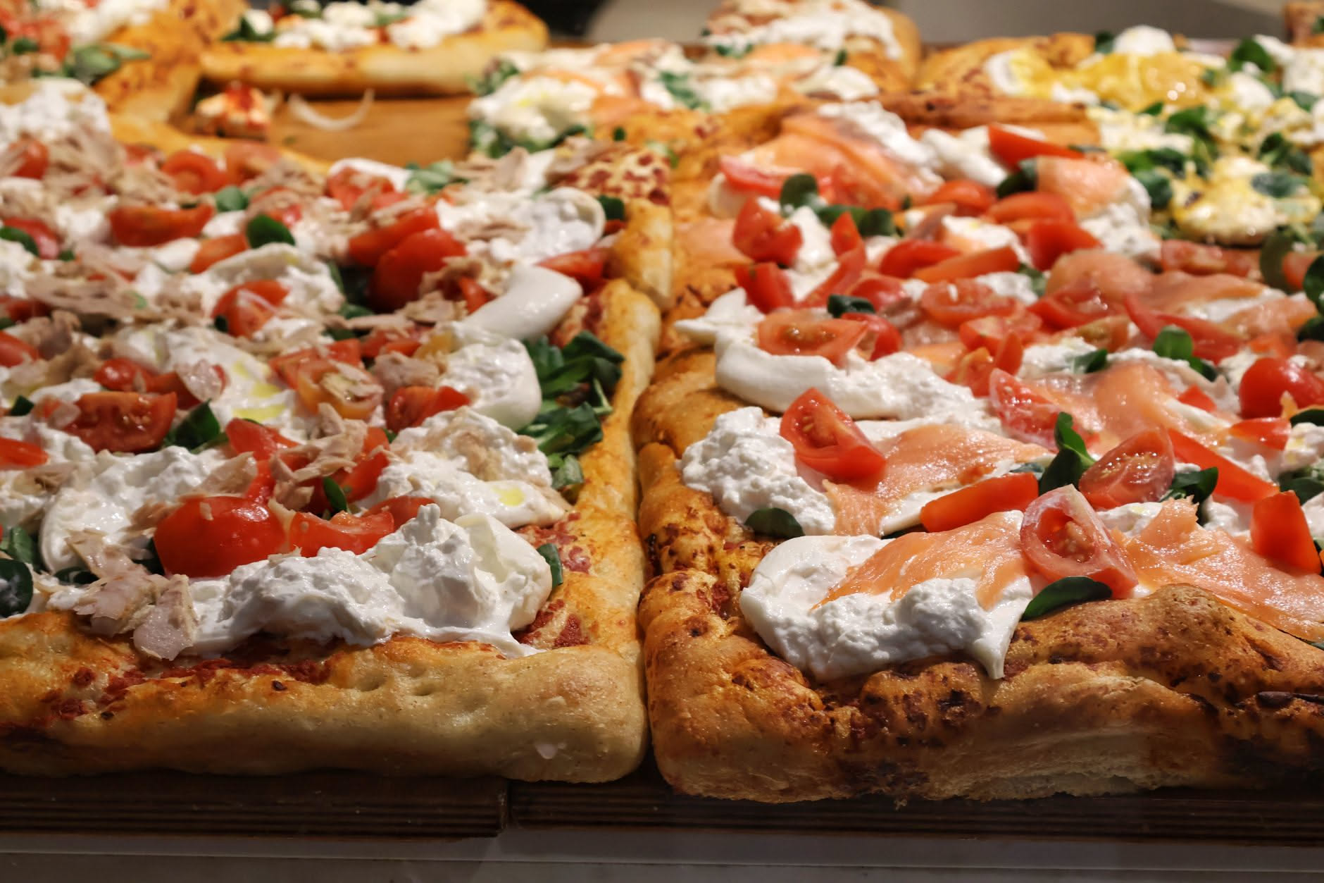 Impasto di pizza piatto in una ciotola bianca di ceramica, con superficie liscia senza bolle d'aria, accanto a un termometro e una manciata di farina