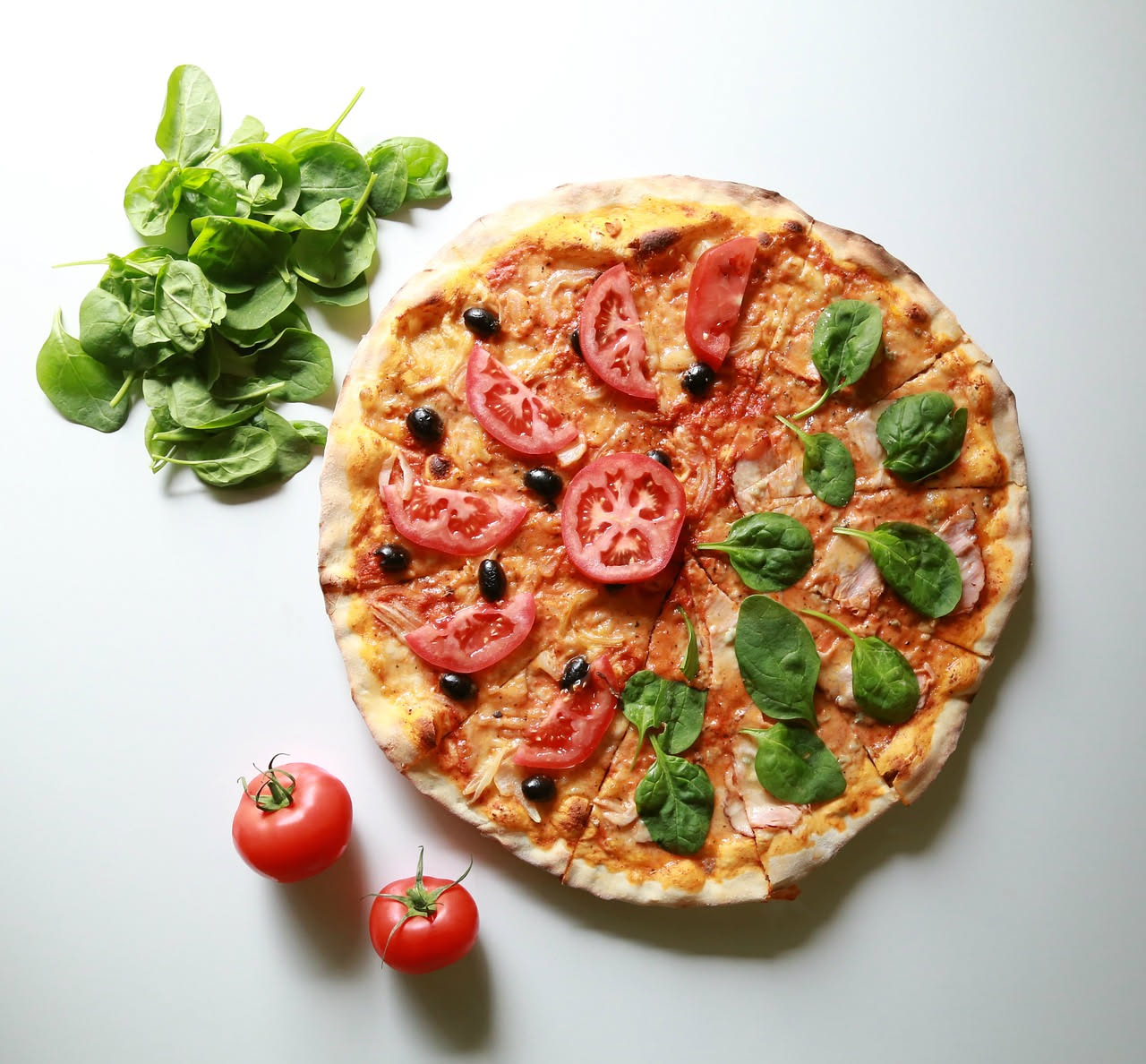 Tre pale di legno per pizza appoggiate su un bancone: una tonda, una quadra con manici e una forata, con impasto sullo sfondo