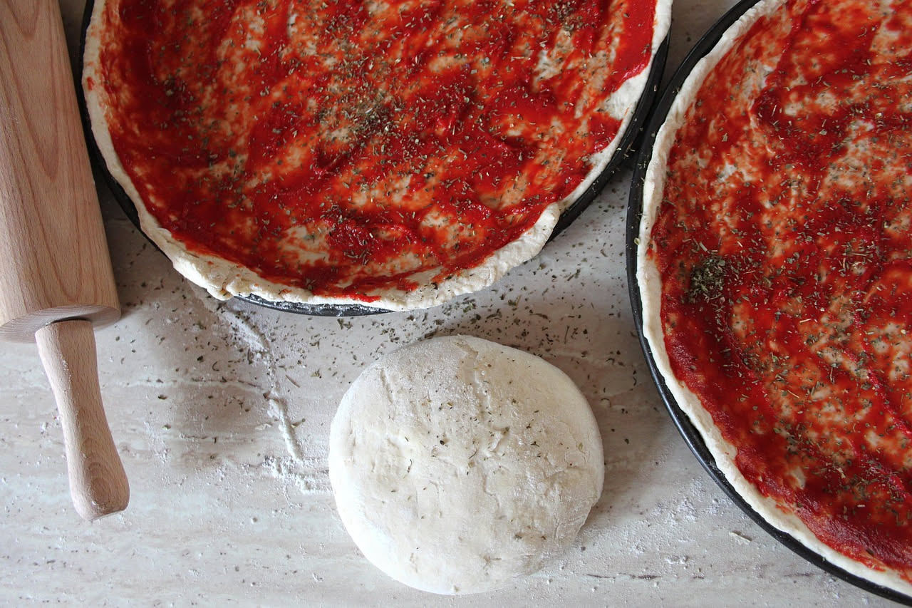 Pizzaiolo che stende un disco di impasto su una spianatoia di marmo, con l'impasto che mostra segni di contrazione ai bordi