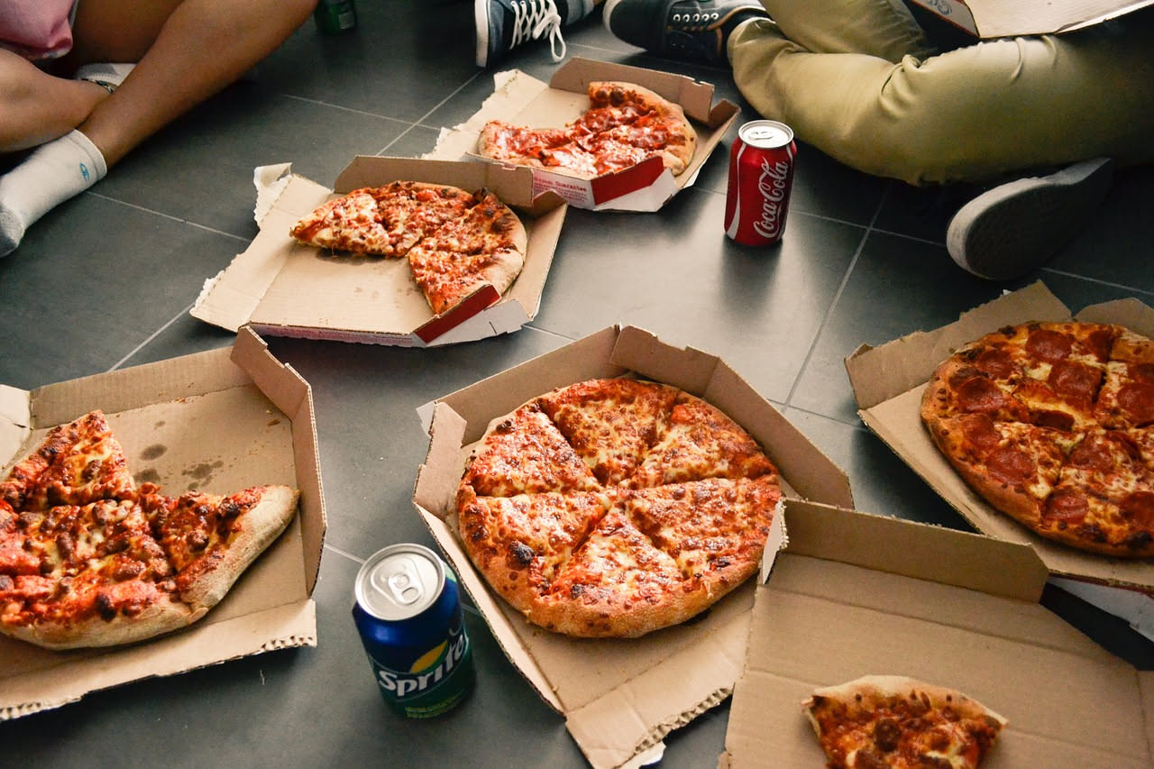 Cartone di pizza aperto che mostra vapore salire dalla superficie, con crosta bagnata e lucida su fondo rosso di salsa