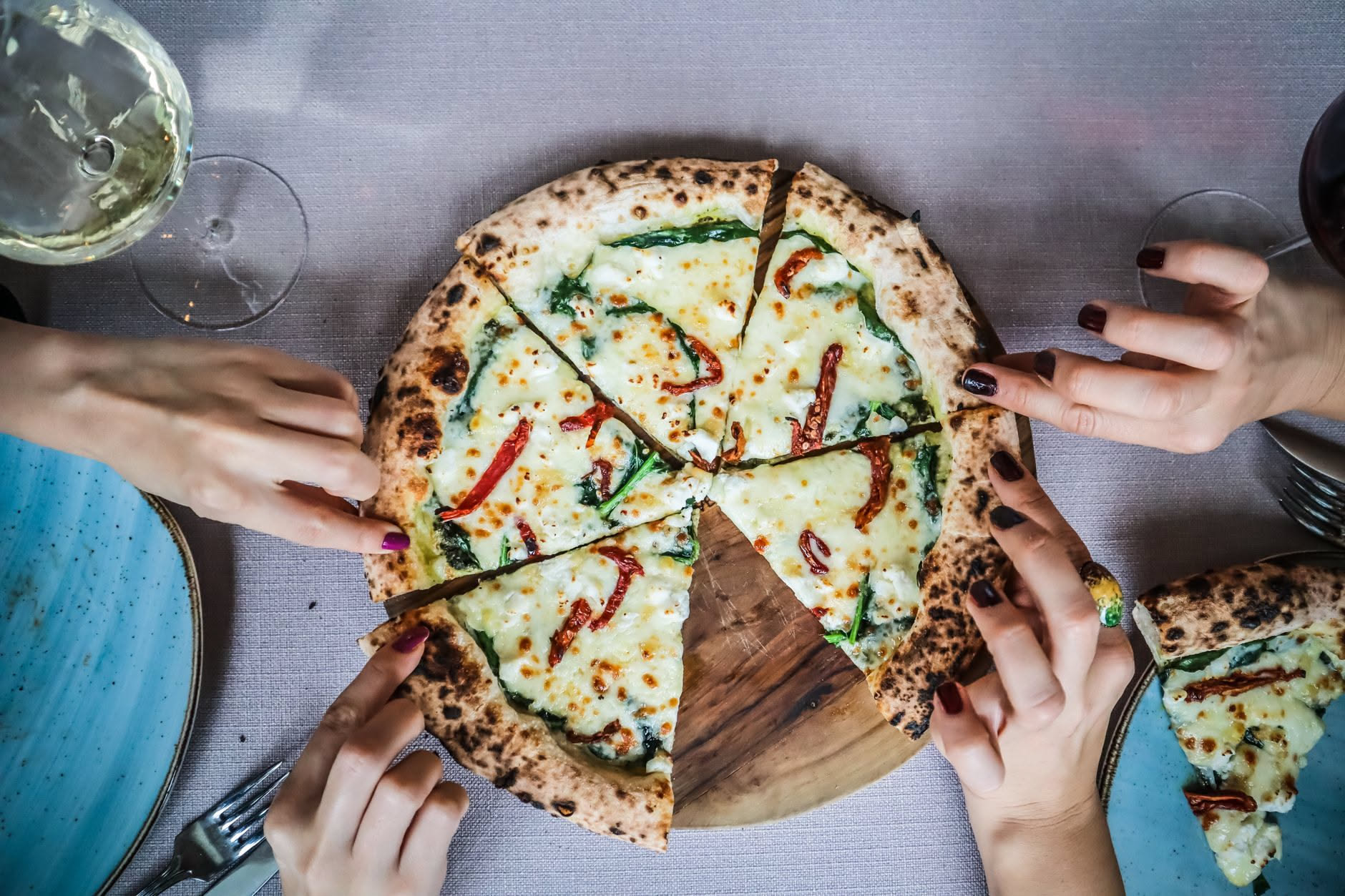 Impasto di pizza su teglia, farina bianca, ciotola d acqua e un cucchiaio di legno su un tavolo di marmo, con sfondo neutro