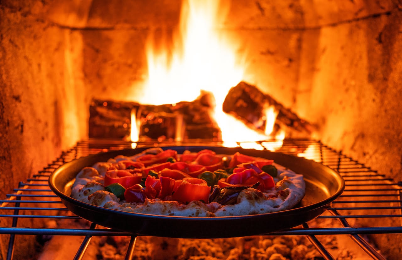 Legna di faggio e quercia naturale stagionata in mucchi ordinati, priva di umidità visibile, accanto a un forno a legna in muratura