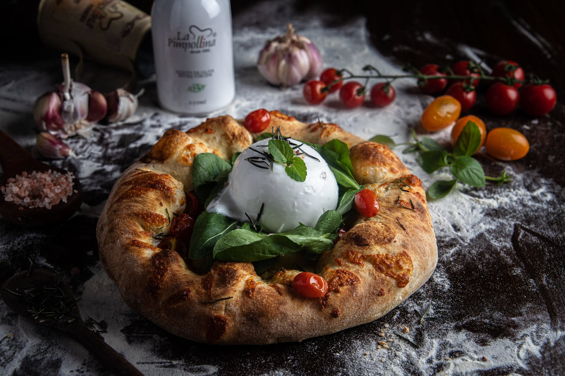 Un panetto di pizza napoletana di 250 grammi posato su una teglia di legno, con forma tonda e superficie liscia leggermente infarinata