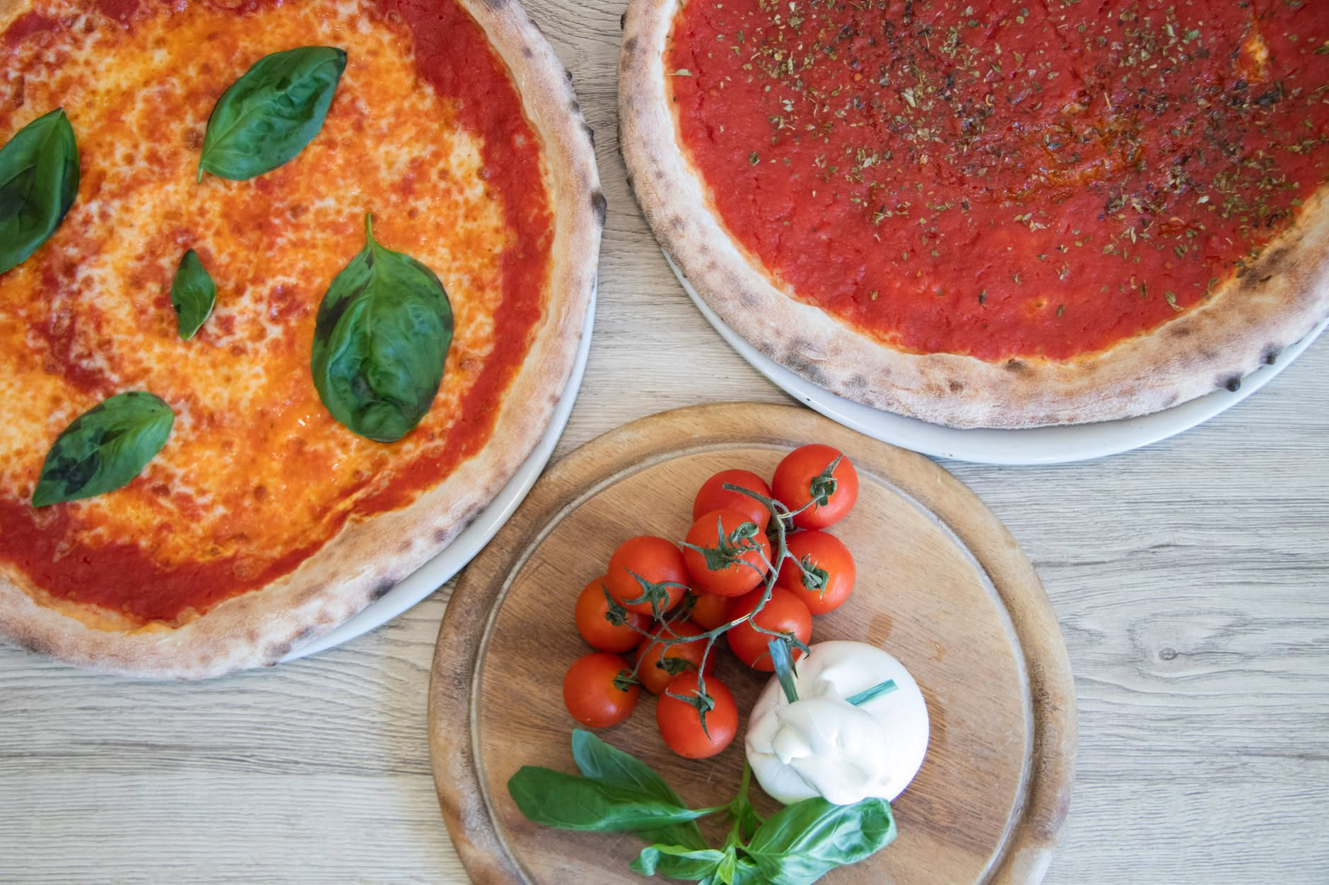 Mani di pizzaiolo che impastano insieme farina bianca e granelli di sale marino grosso in una ciotola di acciaio inossidabile